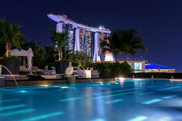 Photo by Pixabay Illuminated Marina Bay Sands hotel above pool at night, capturing Singapore's iconic skyline.