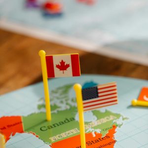 Close-up of miniature Canada and USA flags on a world map depicting North America, symbolizing travel and education.