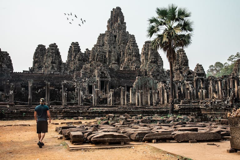 Traveler exploring the ancient Bayon Temple at Angkor Thom, Cambodia, surrounded by stunning architecture.
