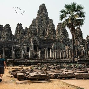 Traveler exploring the ancient Bayon Temple at Angkor Thom, Cambodia, surrounded by stunning architecture.