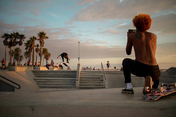 A skateboarder performs a trick at a vibrant skate park in Los Angeles during sunset.