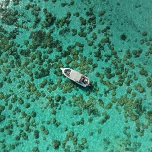 Stunning aerial shot of a boat navigating over the vibrant coral reef waters of Mauritius.