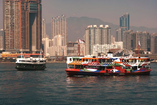 A vibrant ferry sails through Victoria Harbour with Hong Kong skyscrapers in the background.