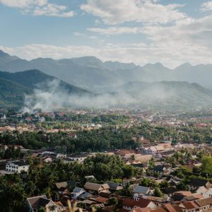Drone view of picturesque valley with village located near mountain range against blue sky with fluffy clouds on sunny summer day